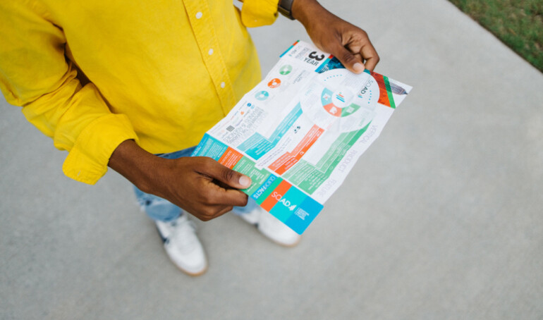 yellow shirt person reading a pocket map